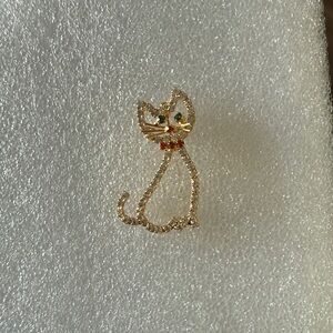 vintage gold-tone rhinestone cat brooch pin with green eyes and a red collar